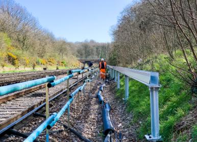 man working at side of rail lines installing cable route system